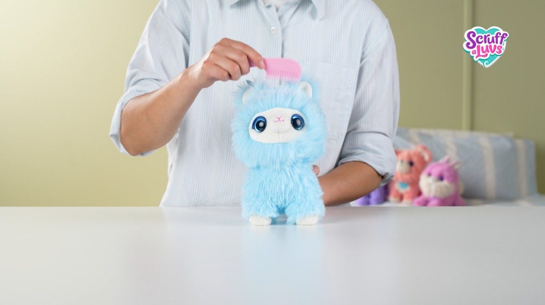 Hands combing a fluffy blue ScruffaLuvs pet on a table